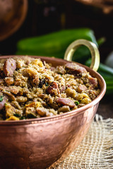 Beans with pork, called tropeiro beans, typical Brazilian food, state of Minas Gerais. Copper pot on rustic wooden background.