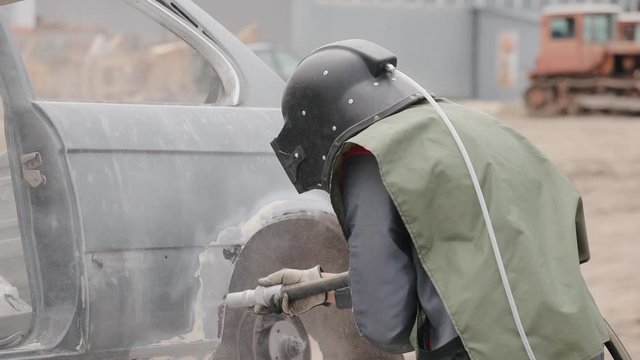 Worker sandblasting metal surface of car. Sandblasting of metal surface of the car by compressed air of the sandblaster gun