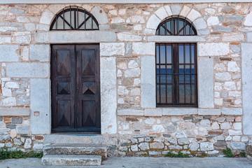 Old architecture stone house with black wooden door and window reflection