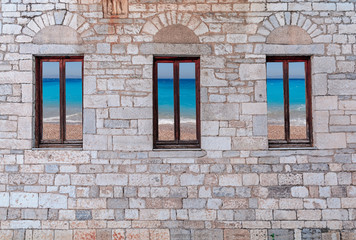 Old stone house with blue sea reflection on windows