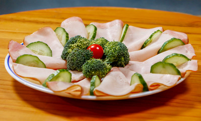 Closeup of bacon, broccoli, cherry tomato, and cucumber on white dish. Homemade healthy nutritious breakfast