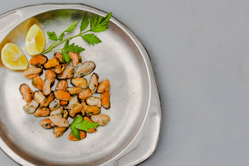 Mussels without shell with lemon slices on a steel tray. Seafood concept. Top view. Space for text