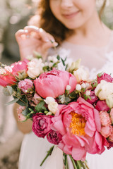 Bride's bouquet close-up, the bouquet consists of red peonies, red and white roses. The bride holds the bouquet 