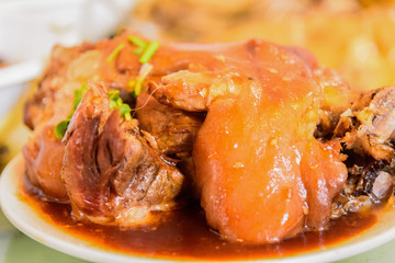 Closeup of braised pork knuckle on white dish, traditional Chinese food