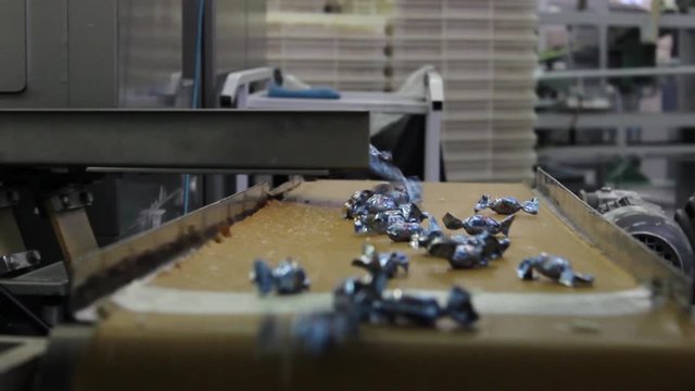 Wrapped Caramel Candies Fall From Above On A Swaying Conveyor Belt In A Candy Factory. The Video Was Taken In Close-up.