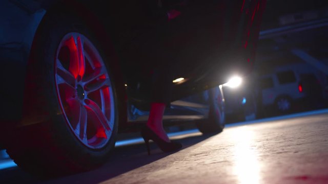 The girl in high heels gets out of the car. Low angle