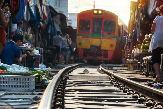 Thailand, Samut Songkhrami, Mae Klong railway market also called Siang Tai. Tourists walk along the train tracks and take photos and selfies of the approaching train.