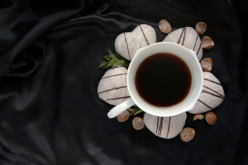 Cup of coffee with cookies in the shape of a heart on a black background