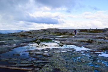 Tourist man on trail to Kjeragbolten. Amazing landscapes of the Norwegian mountains.