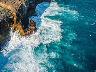 Beautiful scenic aerial landscape of rocky shores, beaches, tide pools and cliffs of Nusa Penida island, Bali, Indonesia. Stormy waves, aquamarine ocean water and sunny day. 
