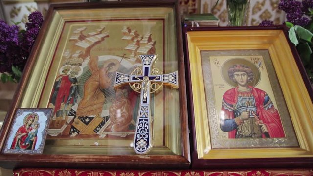 Icon with saints under in a frame under glass. On the glass lies an Orthodox cross with the crucifixion of Jesus Christ.
