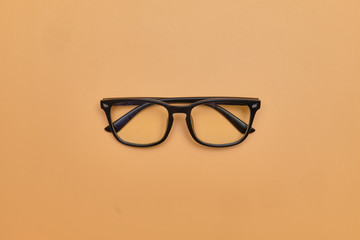 Black glasses on an orange background. Top view.