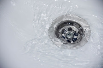 water flow into drain in white bath
