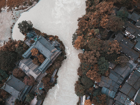 Top down aerial view on the ancient part of Dujiangyan town and irregation system next to Chengdu, Sichuan, China. Old Chinese architecture buildings between the trees next to the Minjiang river.