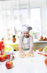 Little girl bakes pies in the kitchen