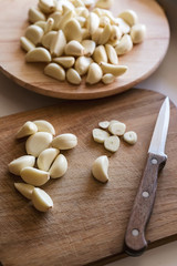 many peeled garlic cloves on wooden cutting boards, knife