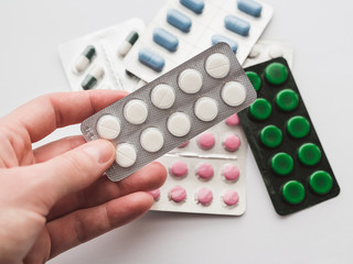 10 tablets in a silver blister in hand on a white background close-up. The concept of medication, treatment