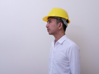 engineer with hands crossed wearing yellow helmet on white background