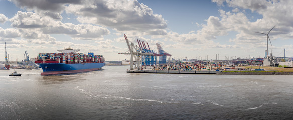 Panorama of a container terminal with arriving container ship and tug in Hamburg 