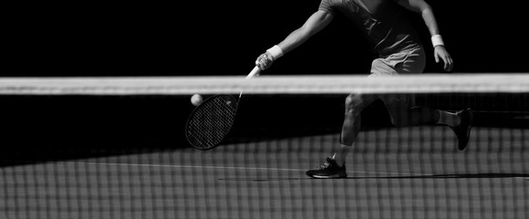 Male tennis player in action on the court on a sunny day. Black and white