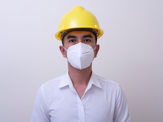 Asian industrial workers wear yellow hard hats, wear protective masks for their health