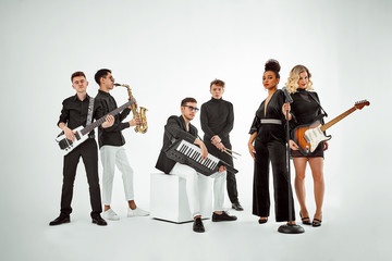 Multiracial music band on a white background. A group of international musicians rehearsing a concert performance. Vocalist, ram, guitarist