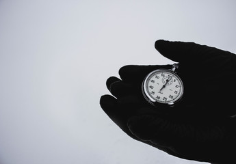 Stopwatch in hands on a white background. Black gloves