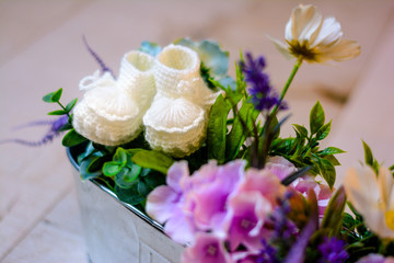 White knitted booties and flowers, baby girl waiting concepts