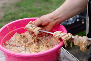 Cooking pork meat skewers, raw meat, fried product on fire, on the grill in nature in little village