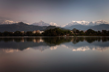 Fototapeta na wymiar Beautiful landscape with Phewa Lake and mountains in background also as reflectaion on lake. Machapuchare-FIshtail, Annapurna and many others. Pokhara, Nepal