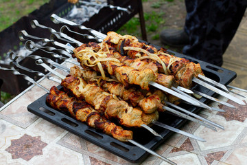 The male hand flips the finished pork skewers on skewers. Cooking meat on a fire in nature