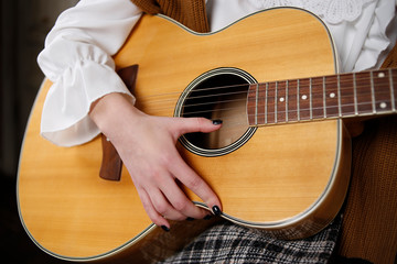 Hands of a young girl with a guitar closeup