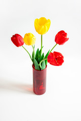 Bouquet of red and yellow tulips in a glass red vase on a white. Banner for congratulations, flower shop, website