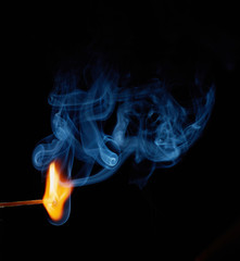 Single matchstick on fire in front of black background.
