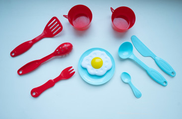 children's dishes of different colors red blue on a white background on a plate fried eggs