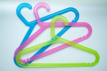 three clothes hangers blue pink yellow on white background