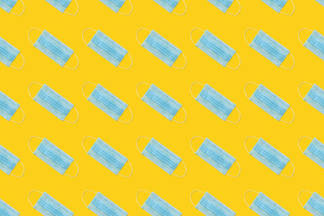 COVID-19 pattern of surgical face masks on yellow background. Protection against coronavirus. Healthcare and medical concept with copy space