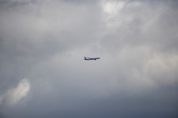 Fototapeta na wymiar Commercial passenger jet aircraft departing Near sunset in a yellow and grey coloured cumulonimbus cloud.