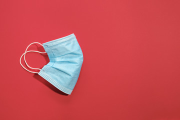 COVID-19 disposable surgical face mask on red background. Protection against coronavirus. Healthcare and medical concept