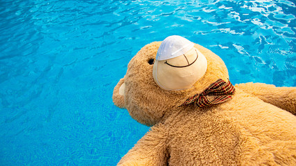 Fototapeta na wymiar Teddy bear with protective face mask inside the swimming pool. Coronavirus concept.