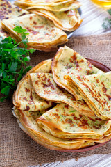 Zucchini thin pancakes with parsley on a wooden table