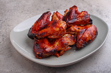 Grilled chicken wings in soy sauce in a plate on a concrete background