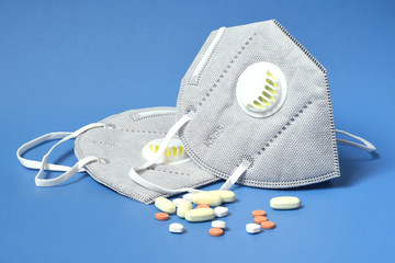 Detail of antivirus protection masks ffp2 or KN95 on blue background with antibiotic and antiviral medicines. Prevention for Coronavirus or COVID-19 and SARS infection.