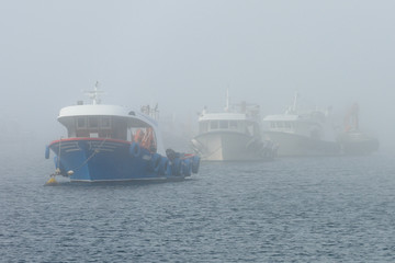 Naklejka premium fishing boats anchored in foggy weather
