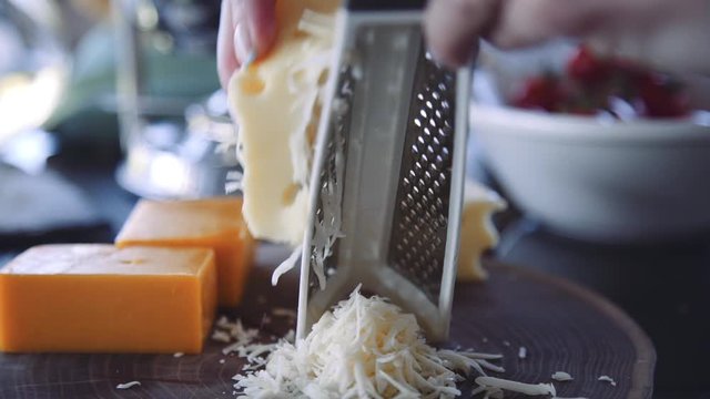 female chef grates the cheese on a grater in slow motion
