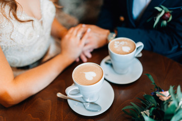 Bride and groom holding hands together. Romantic moment. Coffe cups with hearts