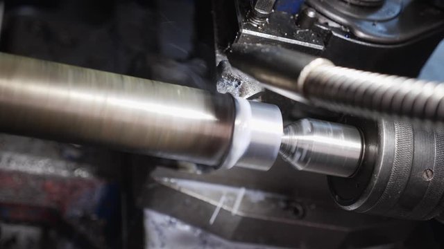 Turning Bench Lathe Machine Working On A Metal Rod Piece - Closeup On The Cutting Edge And Workpiece With Cooling Fluid Flowing