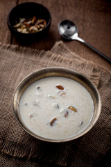 Obraz na płótnie Canvas Kheer or Payasam is a type of rice pudding from the Indian subcontinent, made by boiling milk and sugar and is flavoured with dry fruits and nuts, served in metal bowl.