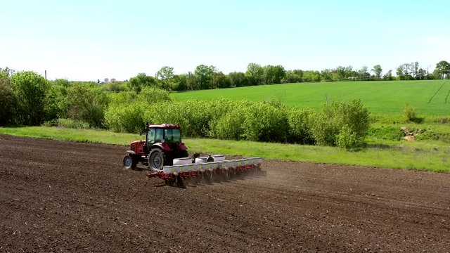 aerial view tractor cuts furrows in farm field for sowing farm tractor with rotary harrow plow preparing land for sowing. Tractor with harrows prepares the agricultural land for planting crop