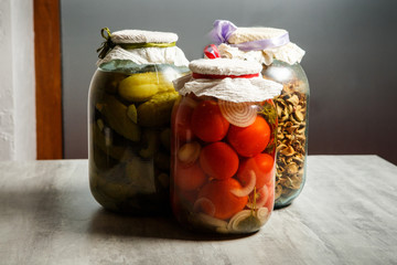 closeup three big clear glass jar with assorted pickled vegetables served on table